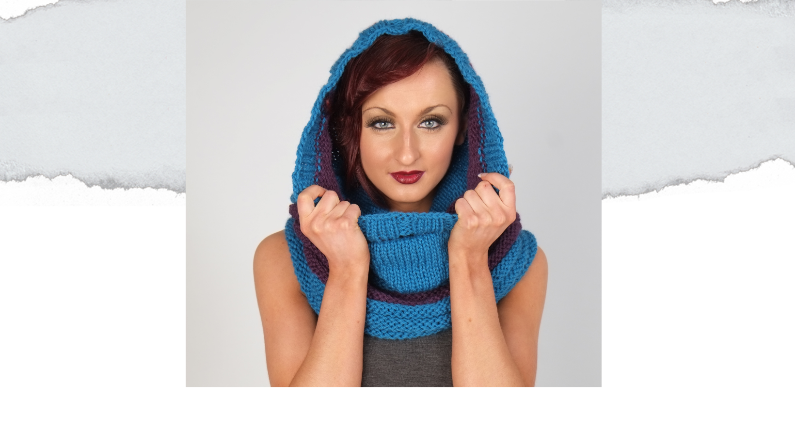 Female wearing a cowl covering head. Cowl knitted in turquoise with purple stripes.