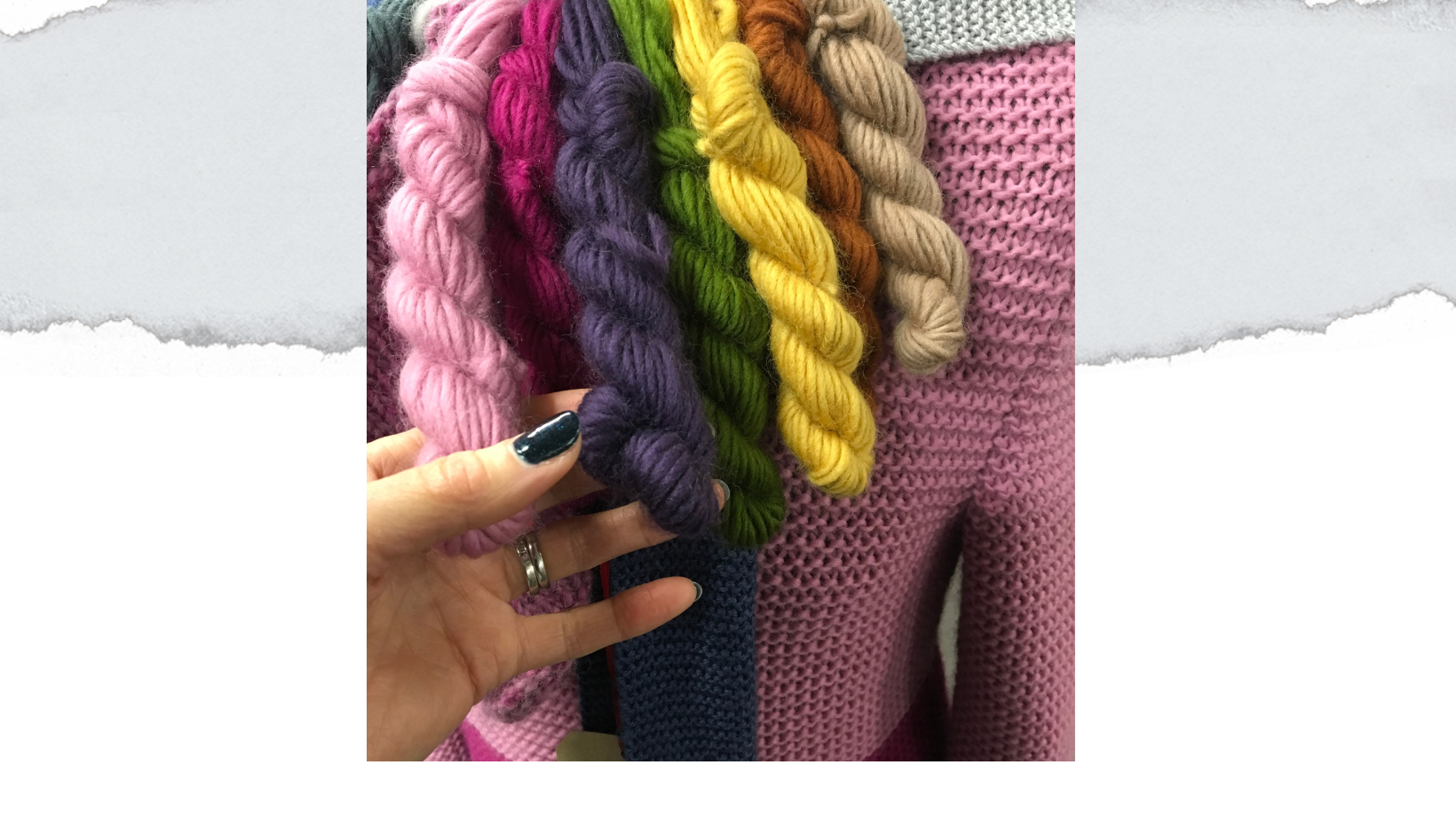 skeins of yarn hanging over a clothes dummy, with a hand holding them
