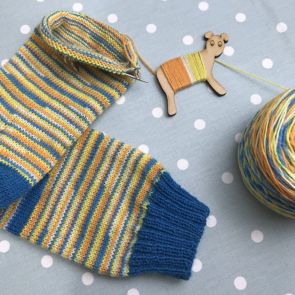 Knitted socks with striped yarn and blue knitted cuffs.
