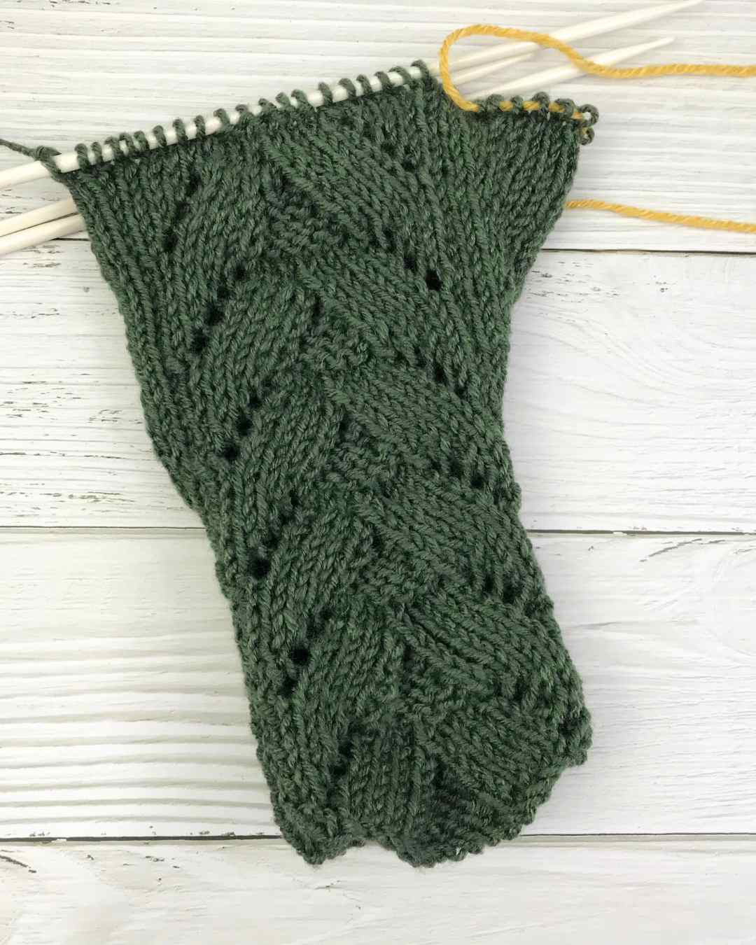 Knitted fingerless mittens showing thumb stitches on hold