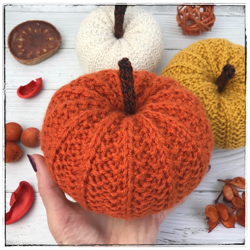 Hand knitted pumpkin in rust coloured yarn with mustard pumpkin in background