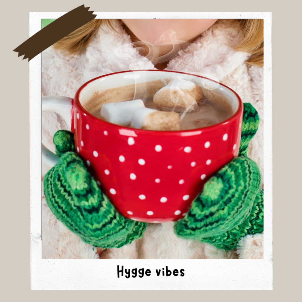 Hands wearing knitted mittens, holding a warm cup of hot chocolate to visualise the concept of Hygge
