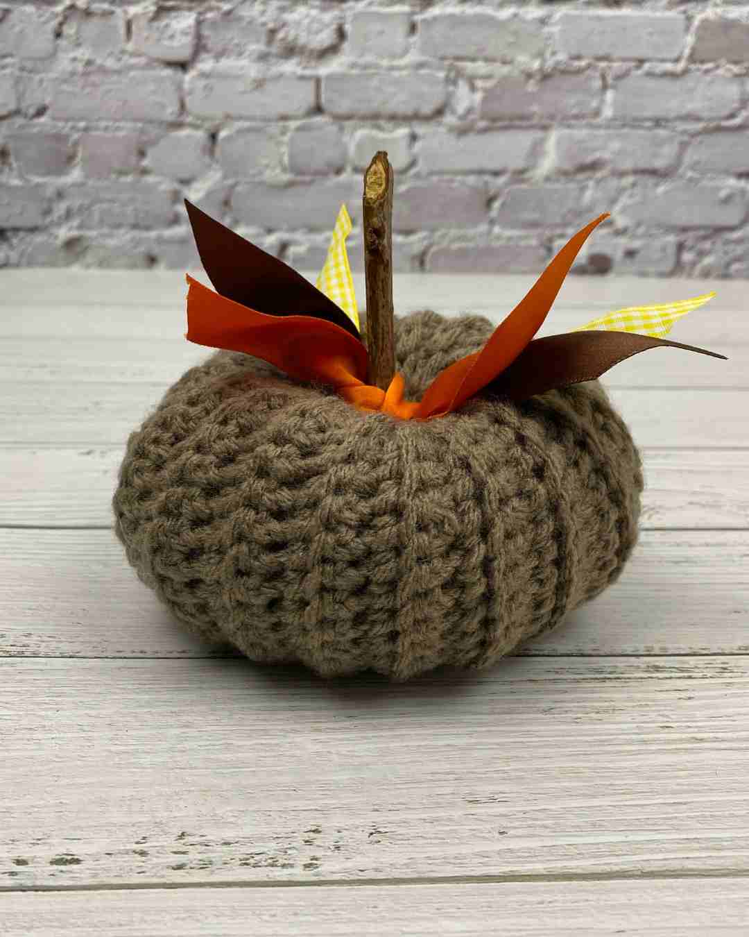 Brown pumpkin with orange ribbon and twig, made from easy crochet pumpkin pattern 