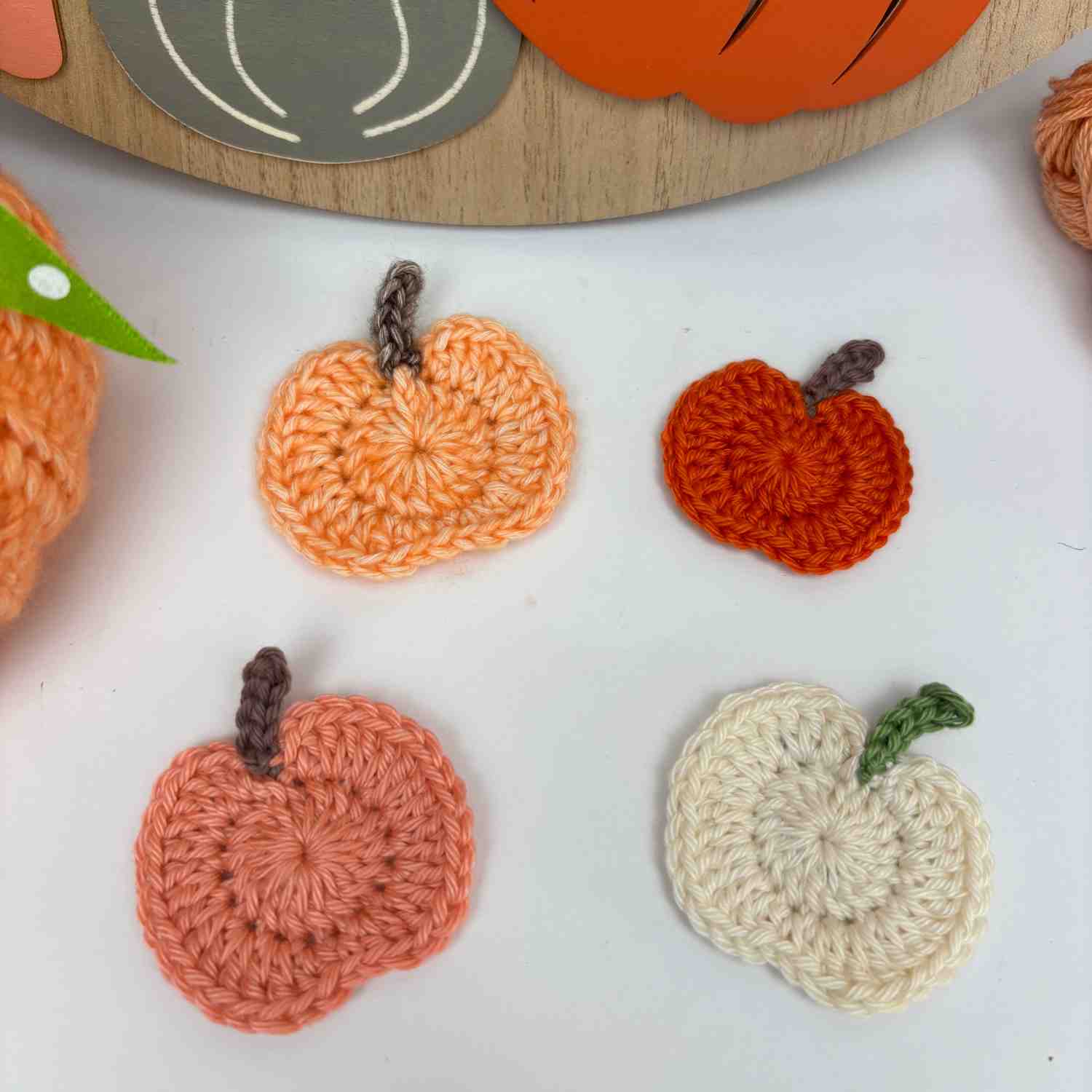 Four Crochet Pumpkin Motifs scattered on a table, n shades of orange.