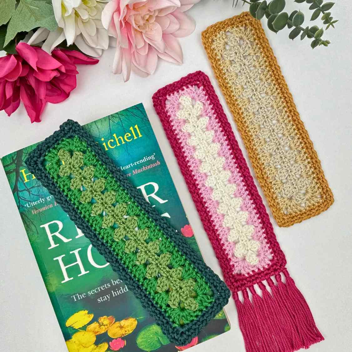 Three crochet bookmarks in festive colours, with one matching a book cover in shades of green.