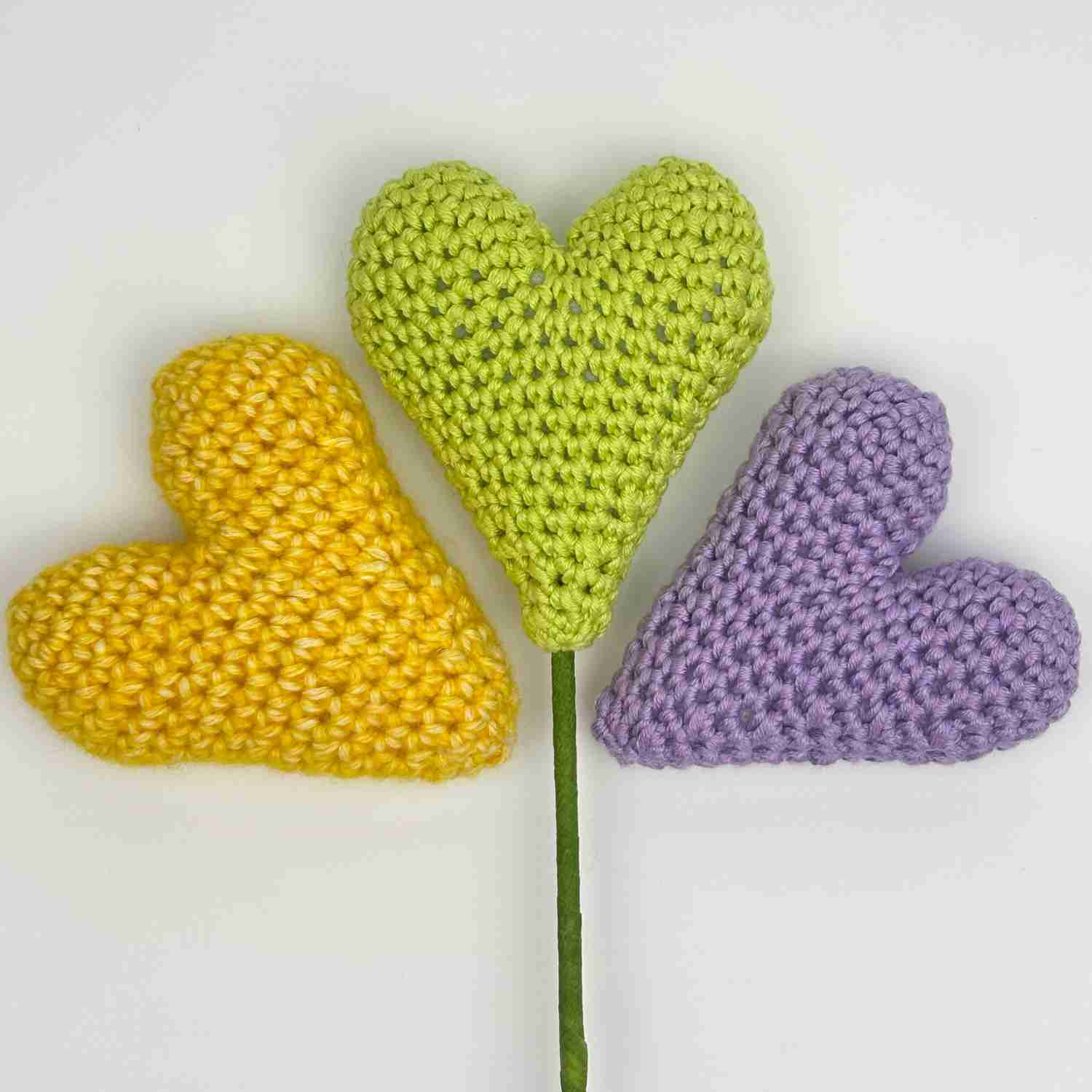 Three hearts in spring colours, with the centre heart on a stick for a plant stem.