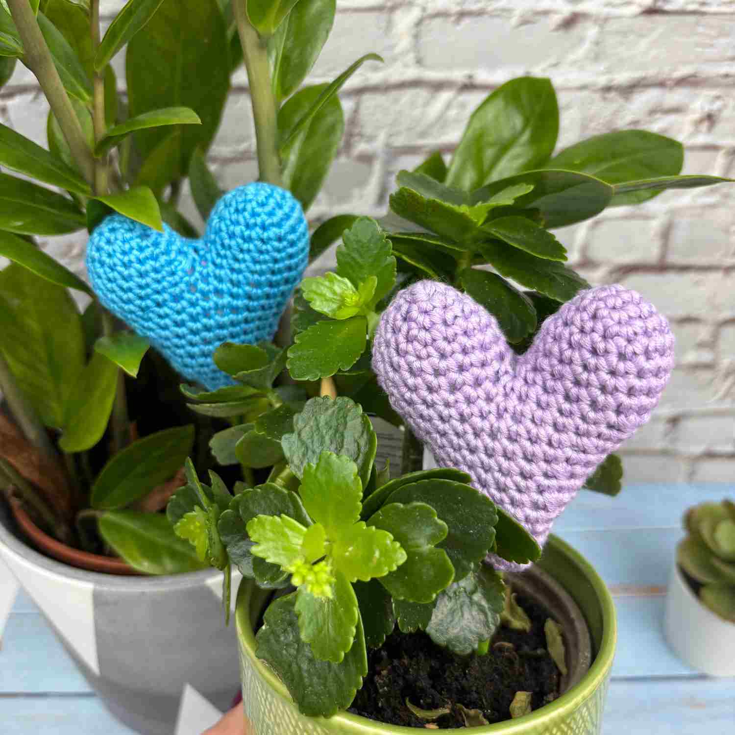 Two crochet amigurumi hearts with sticks, in plant pots