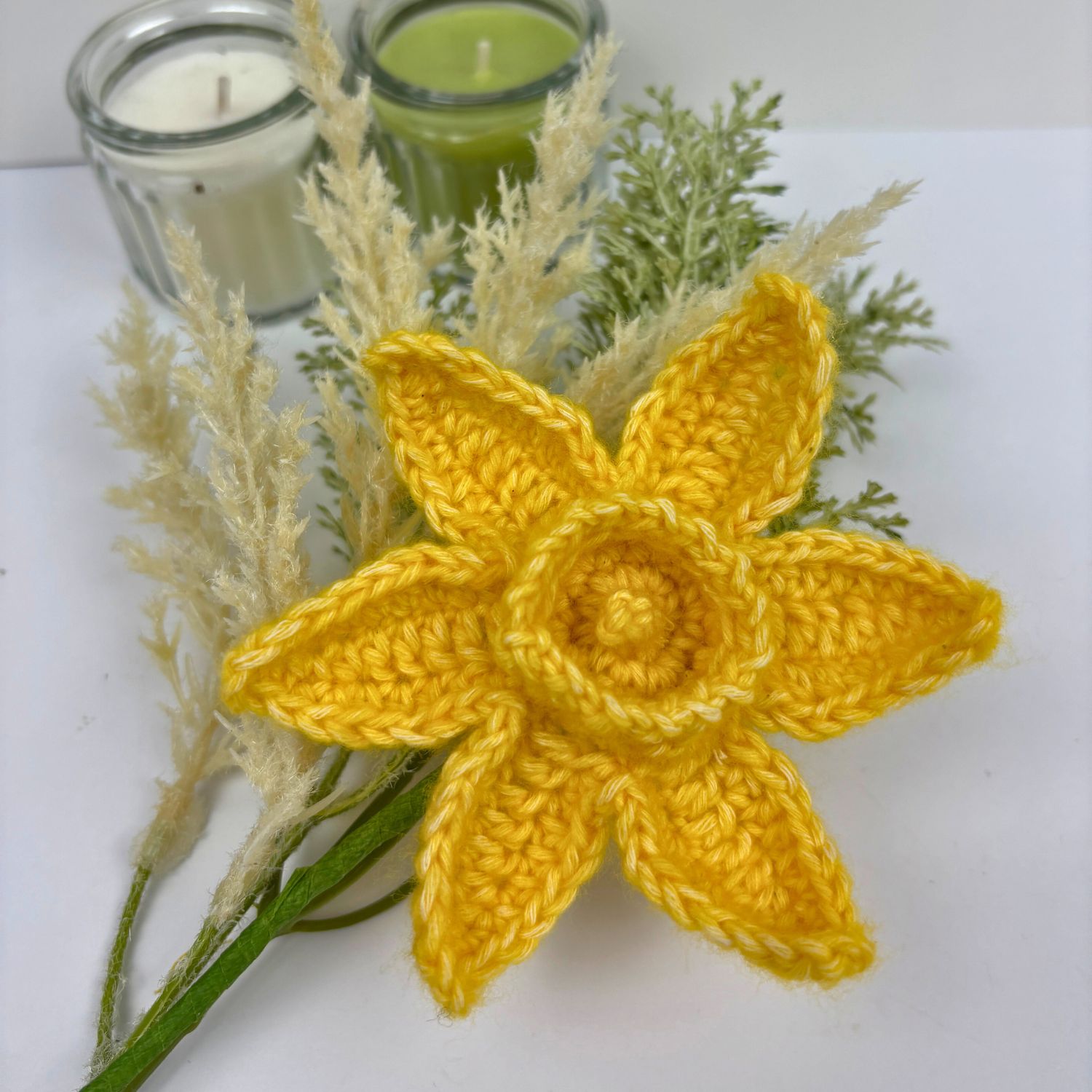 A single crochet daffodil flower with a wire stem.