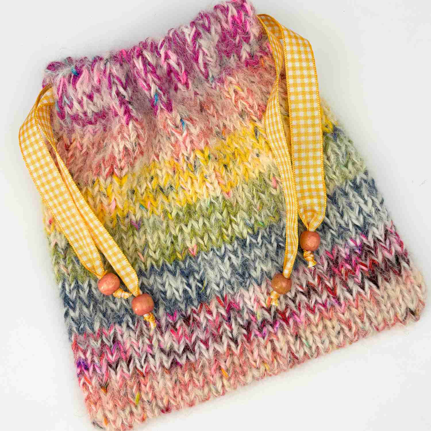 Knitted gift bag made from free knitting pattern with stash yarn. With rainbow stripes and yellow ribbons.