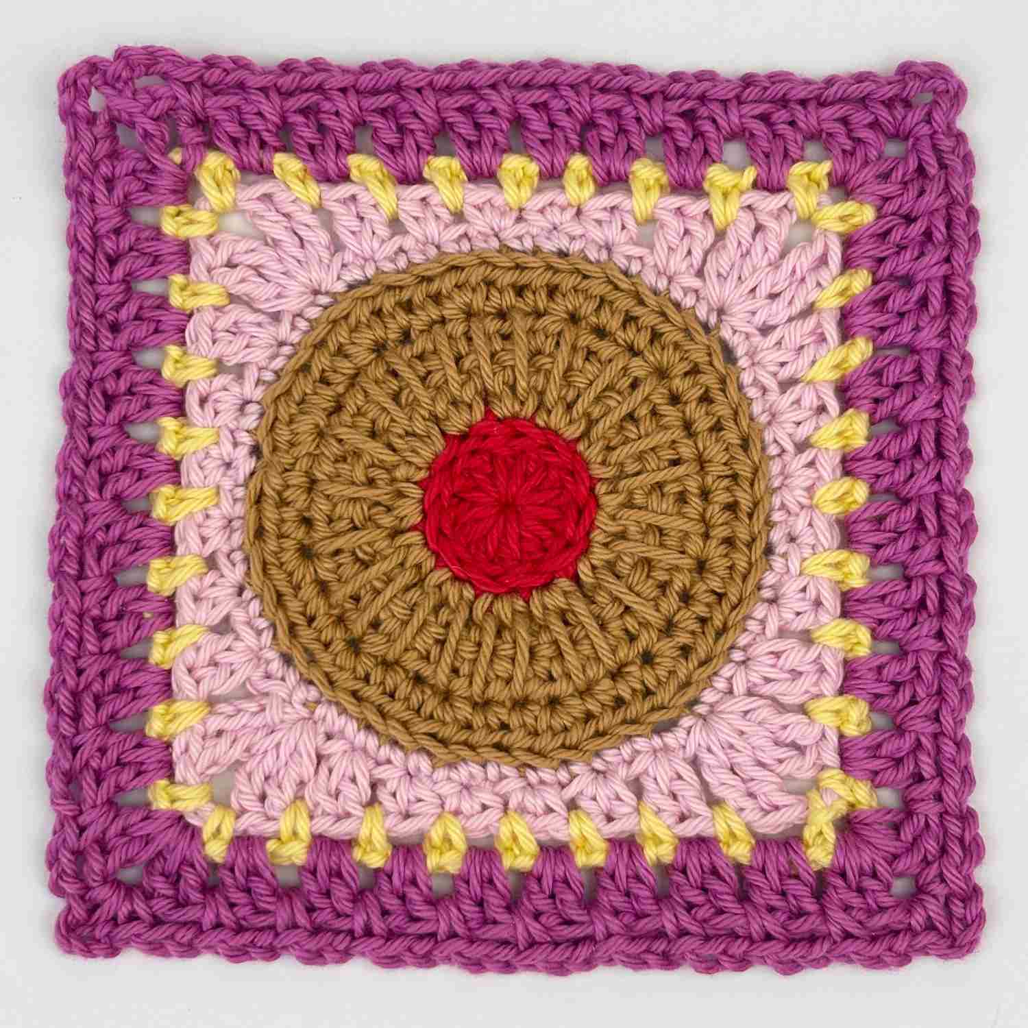 Jammy Ring biscuit granny square from free pattern with a red centre and pink and yellow edges.