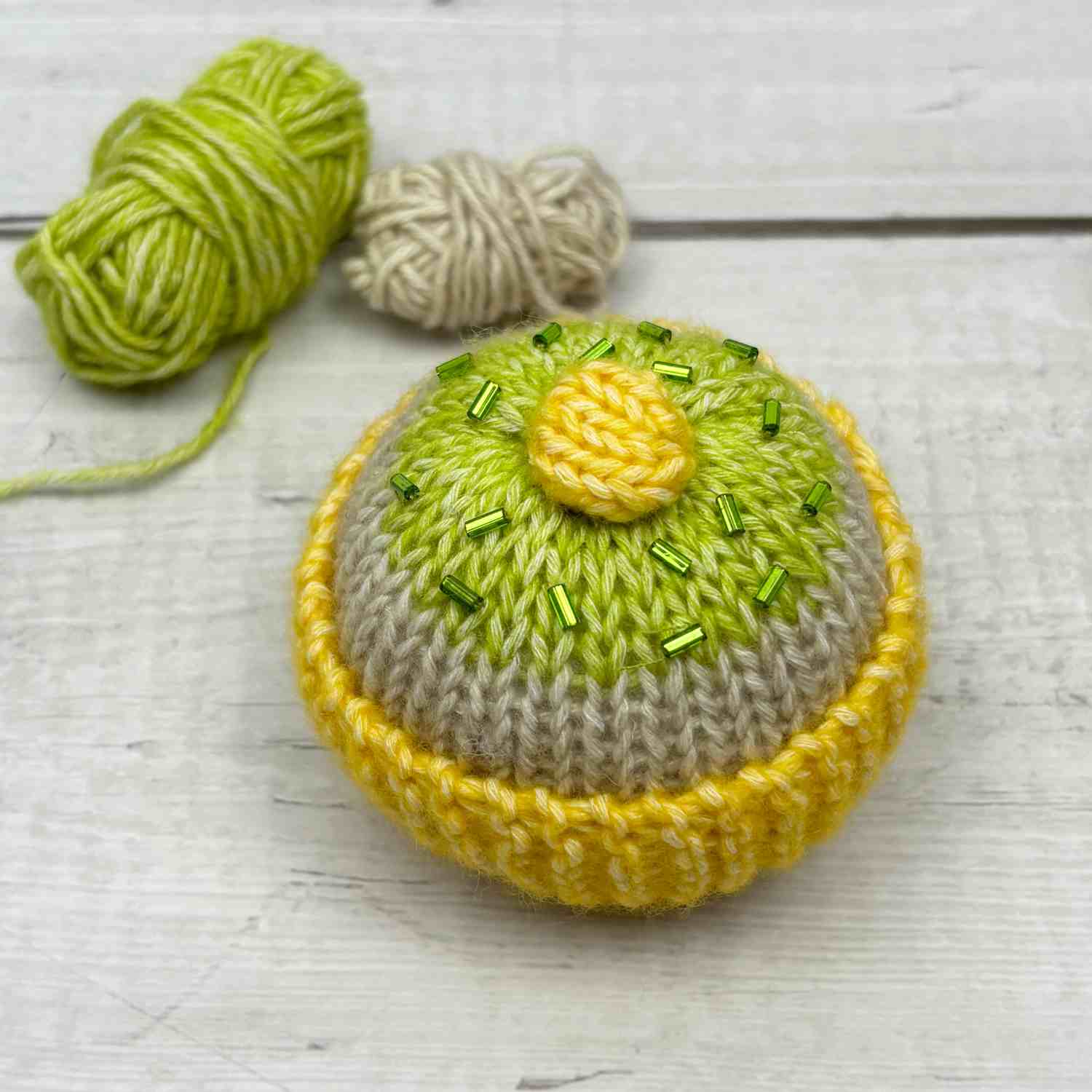 Knitted cake made from a knitted square, topped with green beads for a realistic look.