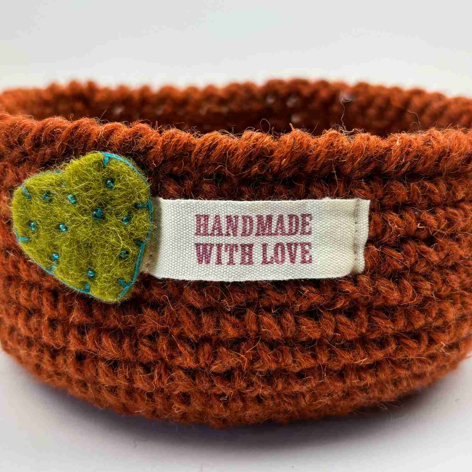 One crochet bowl made from free crochet bowl pattern, with a ribbon across the front with the words 'handmade with love'.