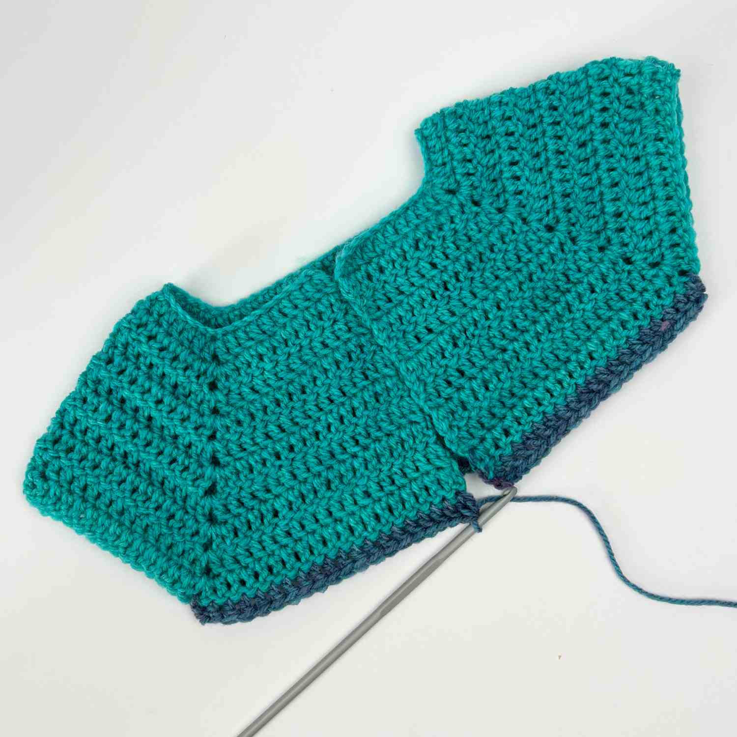 Top of baby cardigan showing sleeves and split for body section.