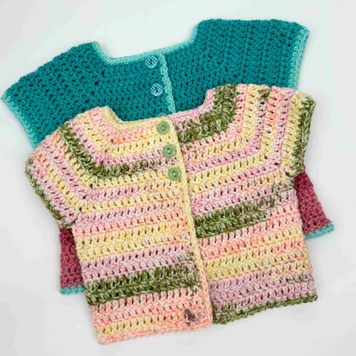Two crochet baby cardigans, one in a bright teal and one in a variegated yarn.