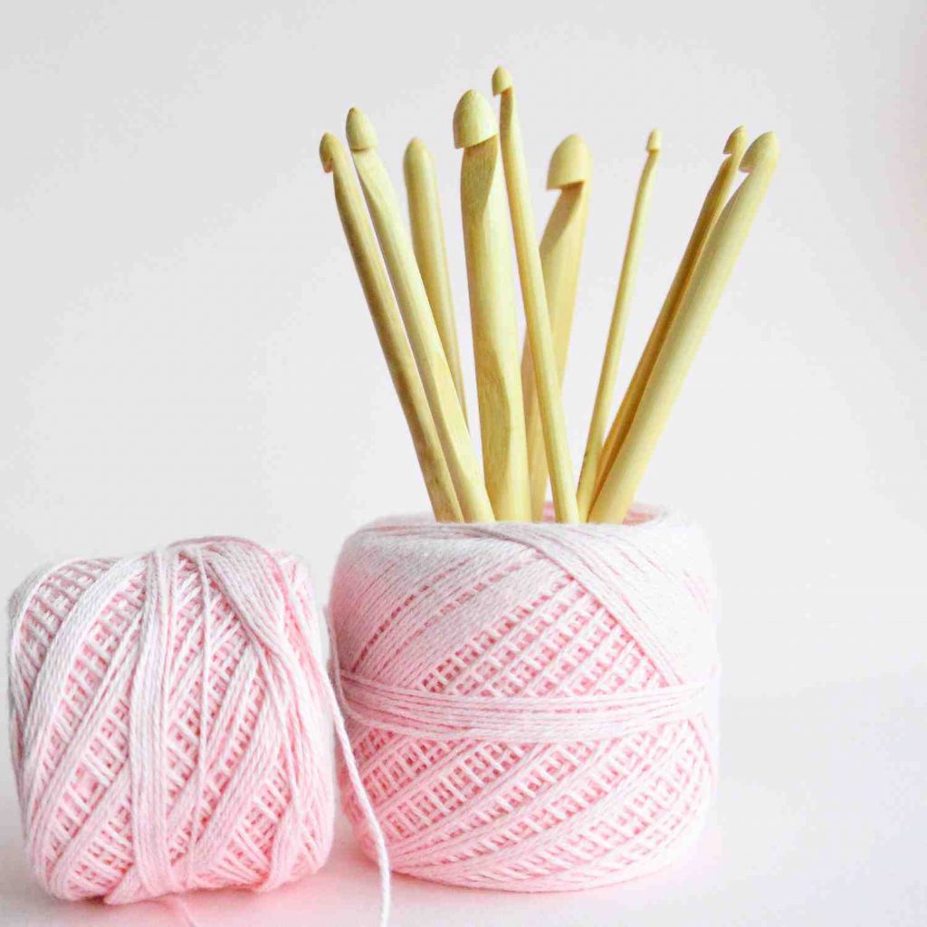 Crochet hooks in bamboo. Different sizes and thicknesses of hook, placed inside a yarn cake.