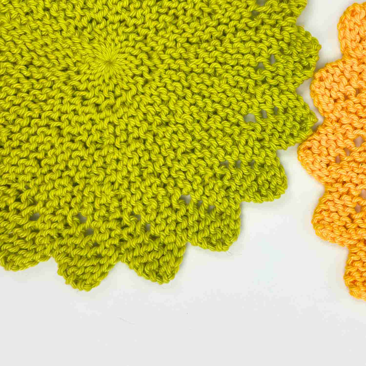 Close up of knitted circle dishcloth pattern made in bright sunflower yellow yarn and pea green yarn. 