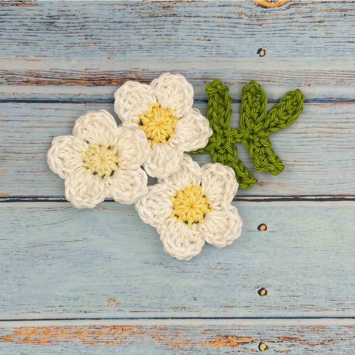 3 crochet flowers and a leaf stem.