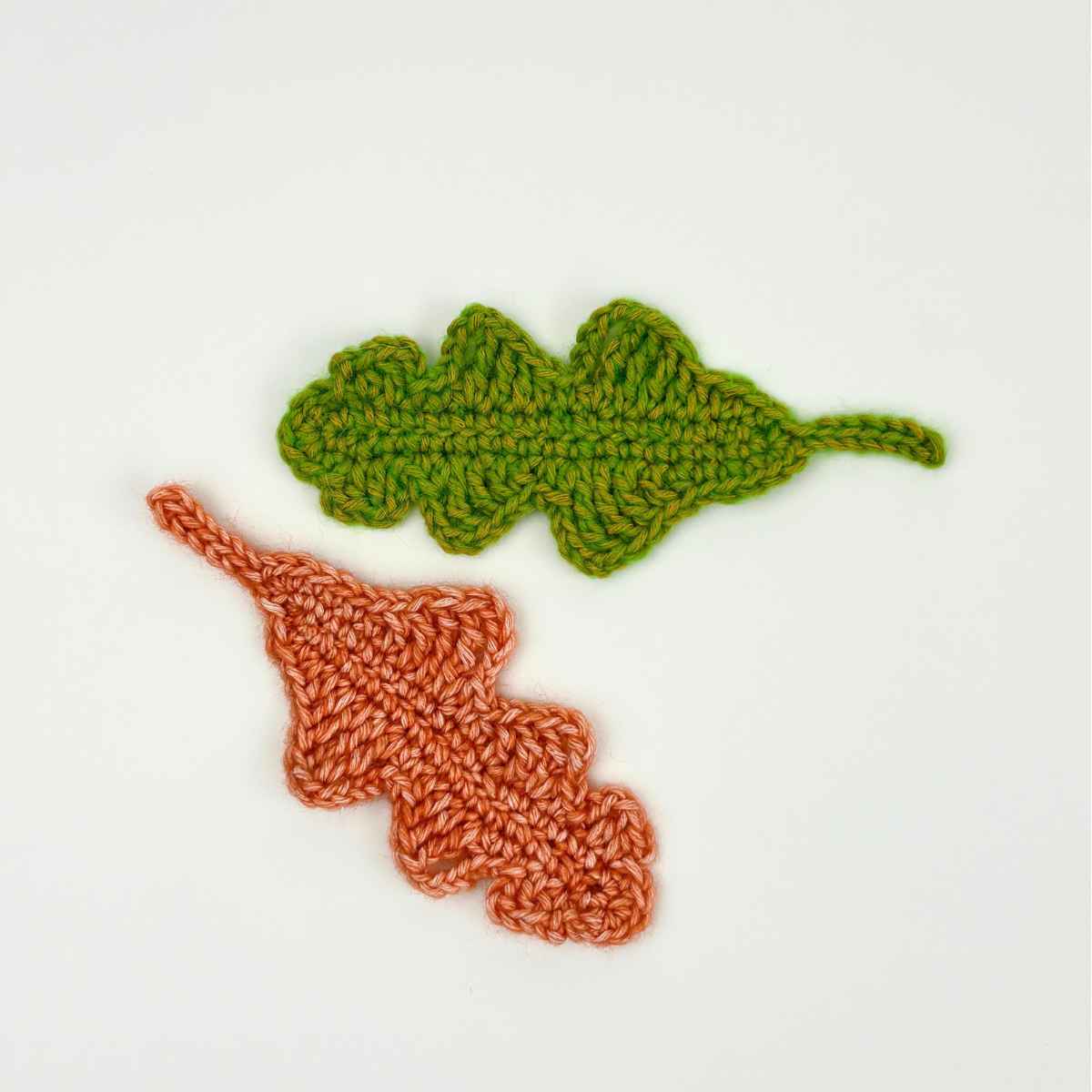 Two crochet oak leaf appliqué made from free pattern. Shown in Orange and Green yarn.