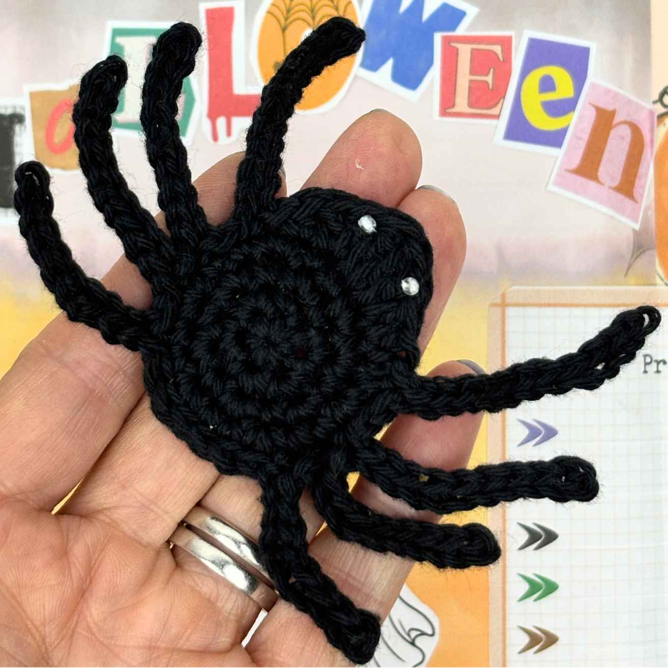 Crochet Spider Appliqué Motif made from free crochet pattern, shown in Purple cotton yarn on palm of hand.