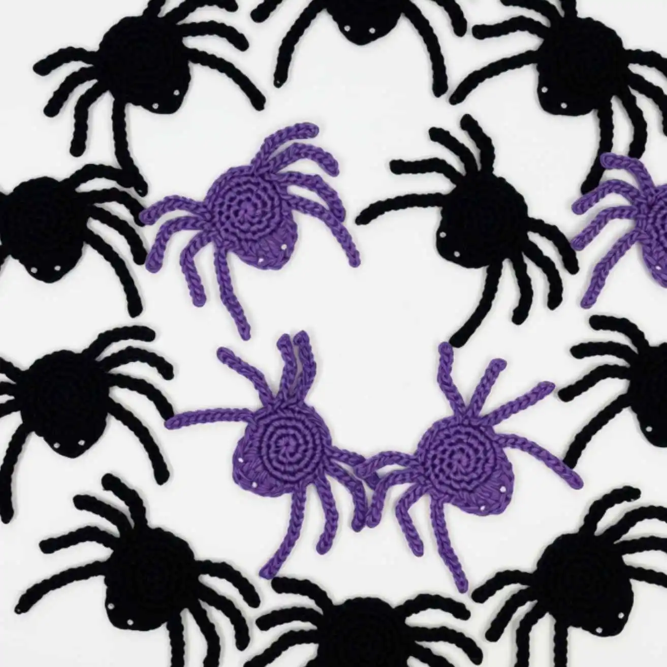 Lots of flat crochet spider motifs in black and purple yarn.