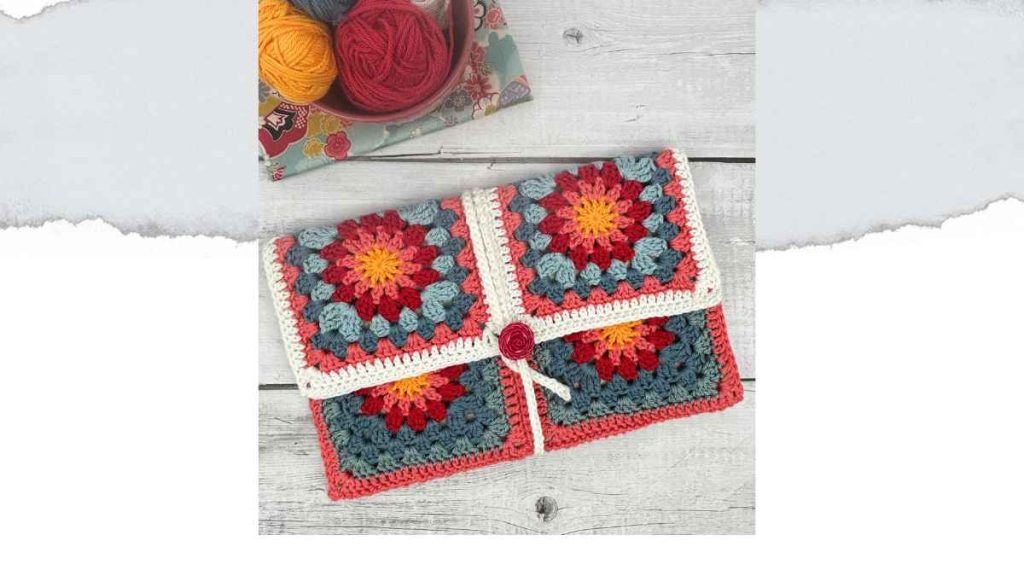 Crochet book sleeve made from six granny squares with golden yellow sun centres, in coral, teal and white cotton yarn, with a novel tucked inside.
